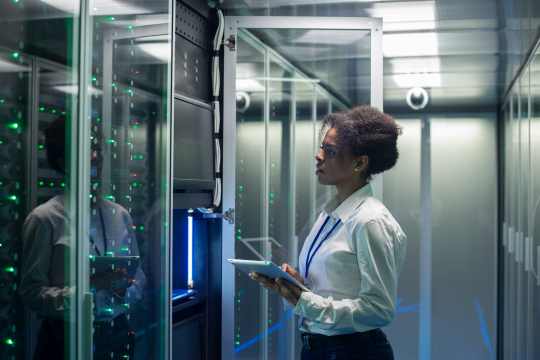 Black woman, data center engineer with tablet looking at a data center rack