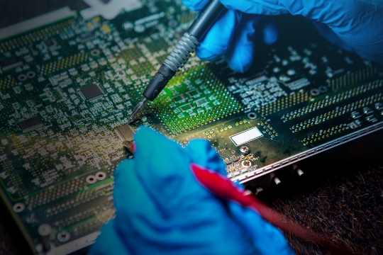 Celestica employee holding an electronic board.