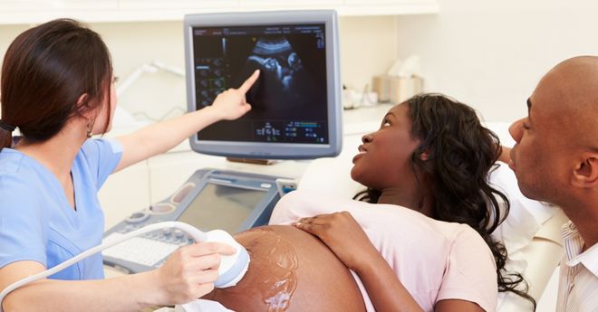 Female patient receiving an ultrasound with her male partner and ultrasound technician. 