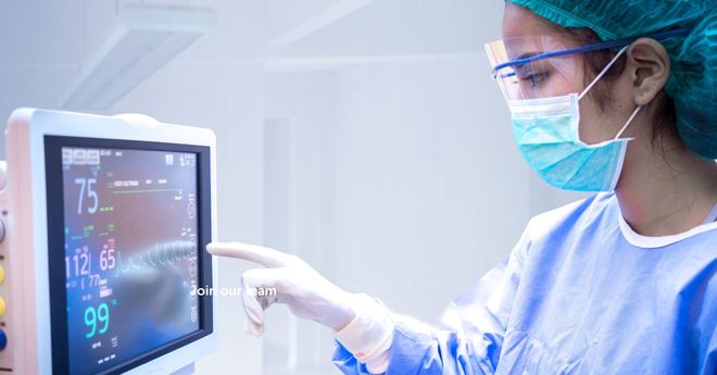 Healthcare professional looking at a digital screen displaying a patient's vitals. 