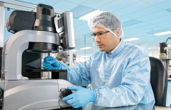 Celestica health tech employee using a microscope